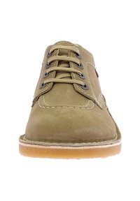 Scarpa stringata in suede color tan con un design cucito, suola in gomma e occhielli in metallo. Presenta un accento rosso sul lato.