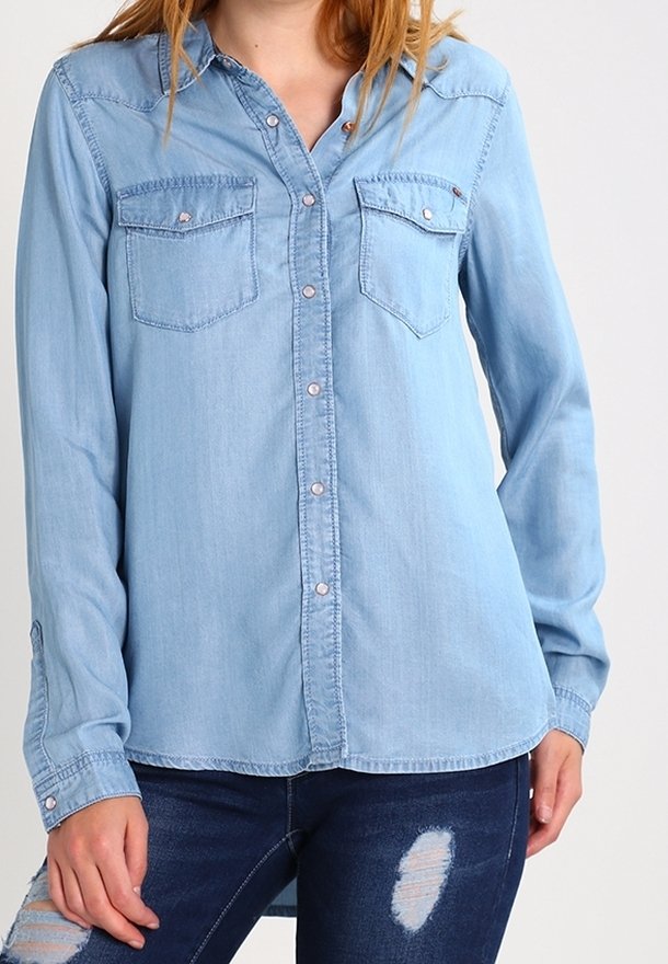 Ljusblå denimskjorta med långa ärmar, knäppning framtill och två bröstfickor. Har en mjuk textur och klassiska designelement.