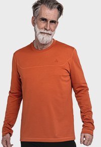 Langärmliges Shirt aus leuchtend orangefarbenem Stoff, mit einem strukturierten Muster, rundem Ausschnitt und dezenten Details auf der Brust.