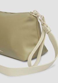 Miękka, jasnozielona torba skórzana o gładkiej fakturze, z płaskim dnem, krótkim uchwytem z znakami firmowymi i subtelnymi detalami w postaci ściegów.