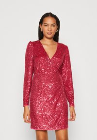 Robe en sequins rouges avec manches longues, décolleté en V profond, taille ajustée et longueur au-dessus du genou. Texture lisse avec un éclat vibrant et un ourlet rose.