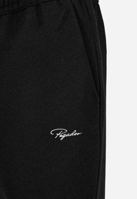 Zwarte sweatpants van zacht materiaal. Voorzien van een elastische tailleband en zijzakken. Witte geborduurde "Pegador" logo bij de zak.