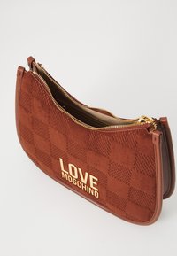 Braune Wildleder-Clutch mit karierter Textur, goldnem "LOVE MOSCHINO"-Logo und teilweise geöffnetem goldenen Reißverschluss, der das beige Innenfutter zeigt.