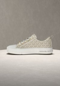 Beiger Leinwand-Sneaker mit MK-Logo-Muster, weißer Gummisohle, goldfarbenen Ösen und hinterer Zuglasche für zusätzlichen Komfort.