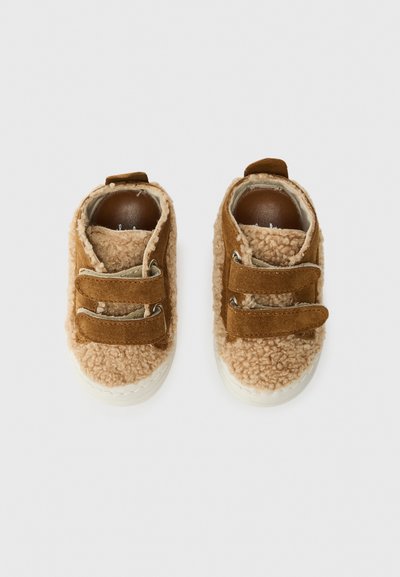 Brune nubuck- og fluffy tekstur sko med to borrelåsremmer, runde tær og en hvit gummisåle.