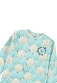 Långärmad skjorta med ett ljusblått och krämfärgat hexagonmönster, texturerat tyg och tryckta detaljer på bröstet.