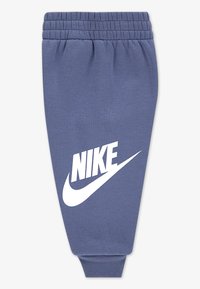 Pantaloni de trening Nike dintr-un material moale, de culoare albastră, cu un design conic. Include un imprimeu alb al logo-ului pe piciorul stâng și un tiv elastic la talie și la gleznă.