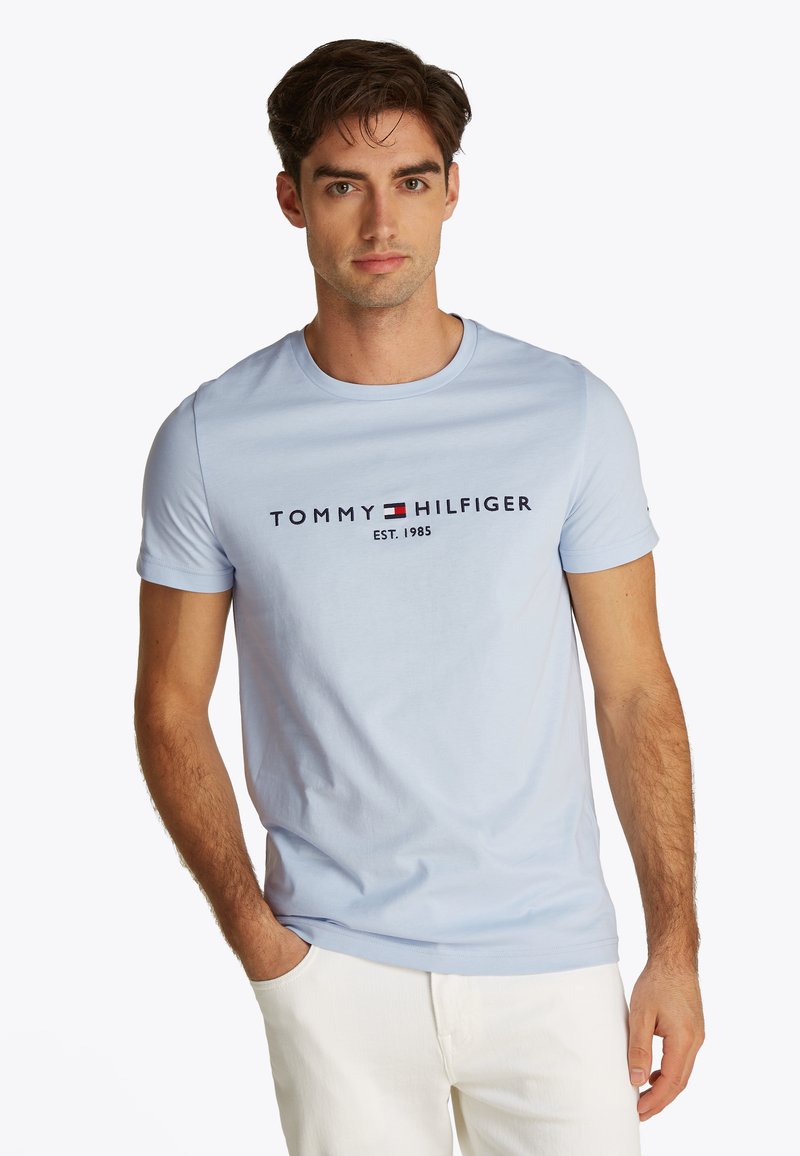 Light blue cotton t-shirt with a crew neck and short sleeves. Features black "TOMMY HILFIGER" logo and established year printed in the center.