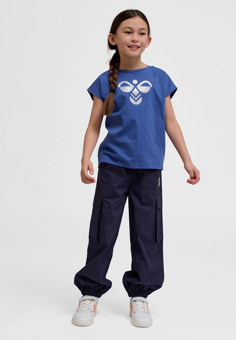 Blaues Baumwoll-T-Shirt mit einem weißen grafischen Design, kombiniert mit navyblauen Cargo-Hosen mit elastischen Bündchen und mehreren Taschen.