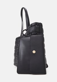 Sac tote en cuir noir avec une texture tissée, un rabat lisse et un bouton-pression doré. Comprend deux poignées pour le transport.