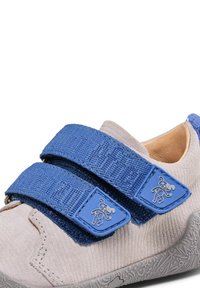 Klittenbandsneakers met een lichtgrijze bovenkant van stof, blauwe gestructureerde banden en rubberen zolen met een speels patroon.