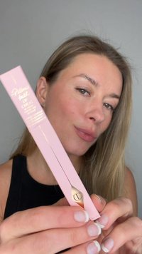 Prodotto per labbra rosa con dettagli dorati, caratterizzato da un applicatore a punta. Il packaging ha una finitura liscia e elementi di branding ben distinti.