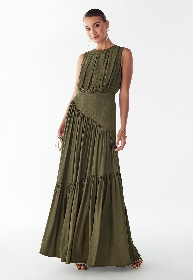 Robe maxi vert olive avec un corsage texturé, un design plissé, une taille cintrée et une jupe à volants. Elle présente une coupe sans manches et des accents subtils.