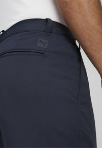 Mornarsko modri hlače z gladko teksturo, s logotipom Puma, zankami za pas in zadnjim žepom.