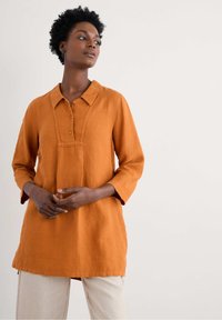 Koperkleurig linnen shirt met een kraag, driekwartmouwen en een knoopsluiting, met een textuur op het voorpaneel.