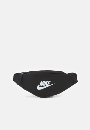 Czarna nylonowa torba na biodra z wyraźnym białym logo Nike. Posiada zamek błyskawiczny oraz regulowany pasek dla pewnego dopasowania. Kompaktowy design.