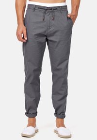 Pantaloni di cotone grigi con chiusura a cordoncino, caratterizzati da orli arrotolati e tasche laterali, abbinati a espadrillas bianche.