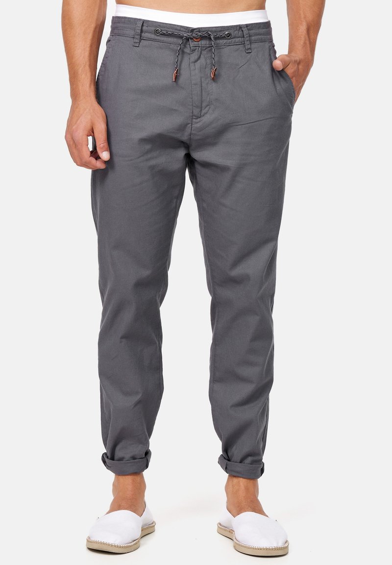 Pantaloni di cotone grigi con chiusura a cordoncino, caratterizzati da orli arrotolati e tasche laterali, abbinati a espadrillas bianche.