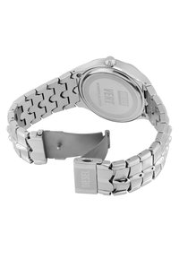 Reloj de acero inoxidable plateado con pulsera de eslabones, caja redonda, cara texturizada y logo de la marca grabado en la parte posterior y en el cierre.