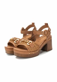 Sandali platform marroni con tomaia in pelle intrecciata, dettagli in hardware dorato, cinturino alla caviglia regolabile e tacco spesso e testurizzato.