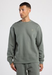 Lichtgroene fleece sweatshirt met een ronde hals, ribbelmanchetten en tailleband. Heeft een klein, getextureerd logo op de borst. Zachte textuur.