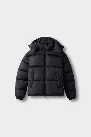 Casaco puffer preto com fecho frontal, gola alta e botões de pressão. Apresenta costuras horizontais e dois bolsos frontais. Material macio e isolante.