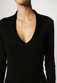 Maglione nero a V con collo a costine, maniche lunghe e design aderente. Tessuto morbido con un'estetica minimalista.