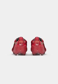 Mizuno Alpha futbola krekli dzīvīgā sarkanā krāsā, ar teksturētu virsu, melniem akcentiem un caurspīdīgiem gumijas nagiem ar tauriņa formas dizainu.