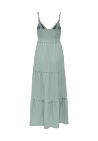 Robe maxi vert clair avec bretelles fines, un corsage plissé et trois volants superposés à la jupe, fabriquée en tissu doux et respirant.