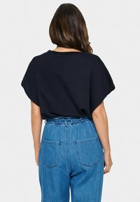 Námořnická oversized tričko s kleslými rameny, doplněné světle modrými džíny s vysokým pasem, které mají elastický pas a zadní kapsy.