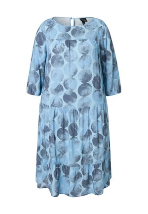 Lyseblå kjole med mørkegrå cirkulært mønster. Har en rund halsudskæring, trekvartærmer og et lagdelt flæse-design. Knaplukning i ryggen.