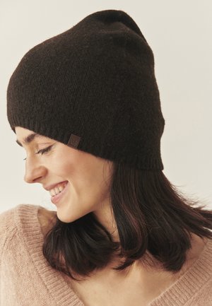 Pruun kudum beanie pehmea tekstuuriga, ümmarguse ülaosaga ja väikese bränditähisega küljel. Soe ja mugav disain.