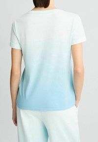 Camiseta de color azul claro con un efecto degradado que va de un azul claro a uno más oscuro, confeccionada en suave algodón, con mangas cortas y un cuello redondo.