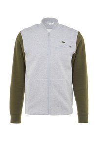 Giacca zip-up grigia e verde oliva, caratterizzata da un colletto alto, due tasche frontali, una tasca sul petto con zip e un piccolo logo sul petto.