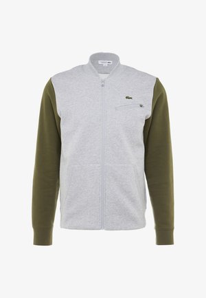 Šedá a olivově zelená bunda na zip se stojáčkem, dvěma předními kapsami, kapsou na zip na hrudi a malým logem na hrudi.