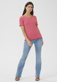 Rood-witte gestreepte T-shirt met korte mouwen, met een scalloped halslijn en zoom, gecombineerd met lichtblauwe uitlopende jeans. Soepele stofstructuur.