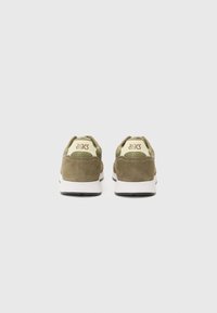 Green suede sneakers with a white sole, featuring textured accents and a beige mesh upper. Brand logo is visible on the heel.
