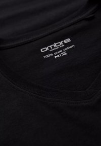 T-shirt noir en 100 % coton pur avec un col en V. Doté d'une texture douce et d'une étiquette visible avec les détails de la marque et d'entretien.