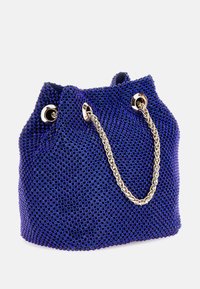 Sac seau en maille violet avec une anse en chaîne tissée. Comprend des œillets métalliques et une surface texturée créée par de petits motifs ronds.