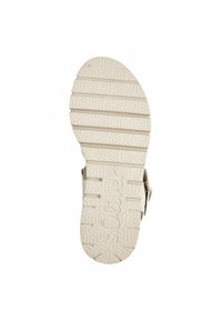 Semelle de sandale beige clair avec motif texturé et empreinte de logo. Présente des ridges et des designs en relief pour une traction et un soutien.