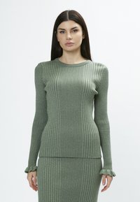Maglione a maniche lunghe verde a coste con scollo rotondo e polsi arricciati, realizzato in un tessuto strutturato e leggermente scintillante.