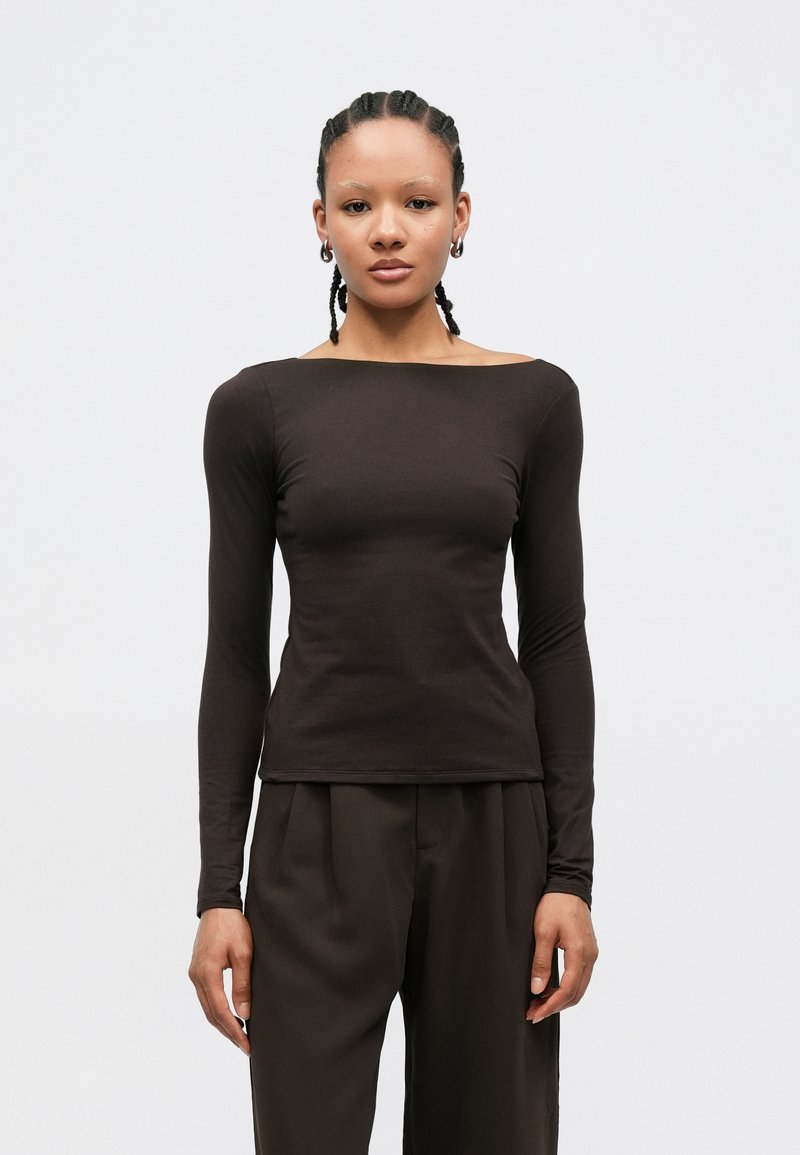 Μπλούζα μακρυμάνικη σε σκούρο καφέ, εφαρμοστή με σχέδιο και boat λαιμόκοψη, κατασκευασμένη από λεία ύλη. Συνδυασμένη με παντελόνια ψηλόμεσα.