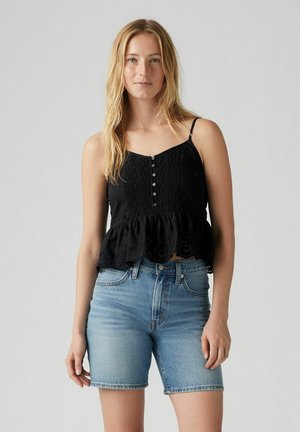 Sort peplum top med justerbare stropper, der har en knaplukning fortil og blondedetaljer. Udfylder lys blå denimshorts.