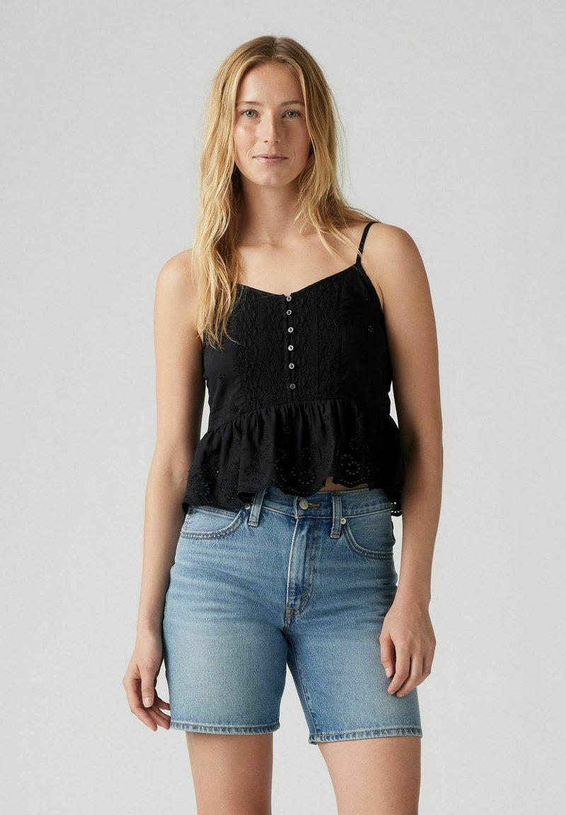 Top peplum nero con spalline regolabili, con chiusura a bottoni e bordo in pizzo. Abbinato a pantaloncini di jeans azzurri chiari.