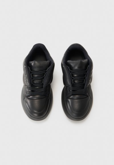 Zwarte leren sneakers met een gladde textuur, ronde neus, gevoerde kraag en bijpassende veters. Voorzien van een gemold logo aan de zijkant.