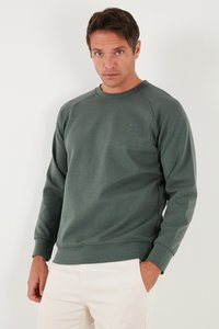 Felpa verde in cotone con scollo rotondo, maniche raglan e logo discreto. Tessuto liscio e vestibilità leggermente rilassata.