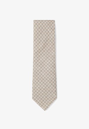 Beige tie with a textured fabric, featuring a patterned design of small white and blue circles, pointed tip and narrow width.
