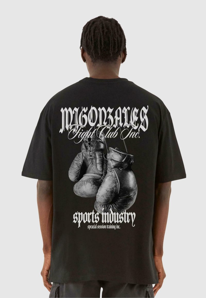 Must on musta T-särk, millel on poksikindade graafika, tekstiga "MIGONZALES Fight Club Inc." ja "sporditööstus" valge värviga. Kõrge mugavuse tagamiseks relaxed fit disain.