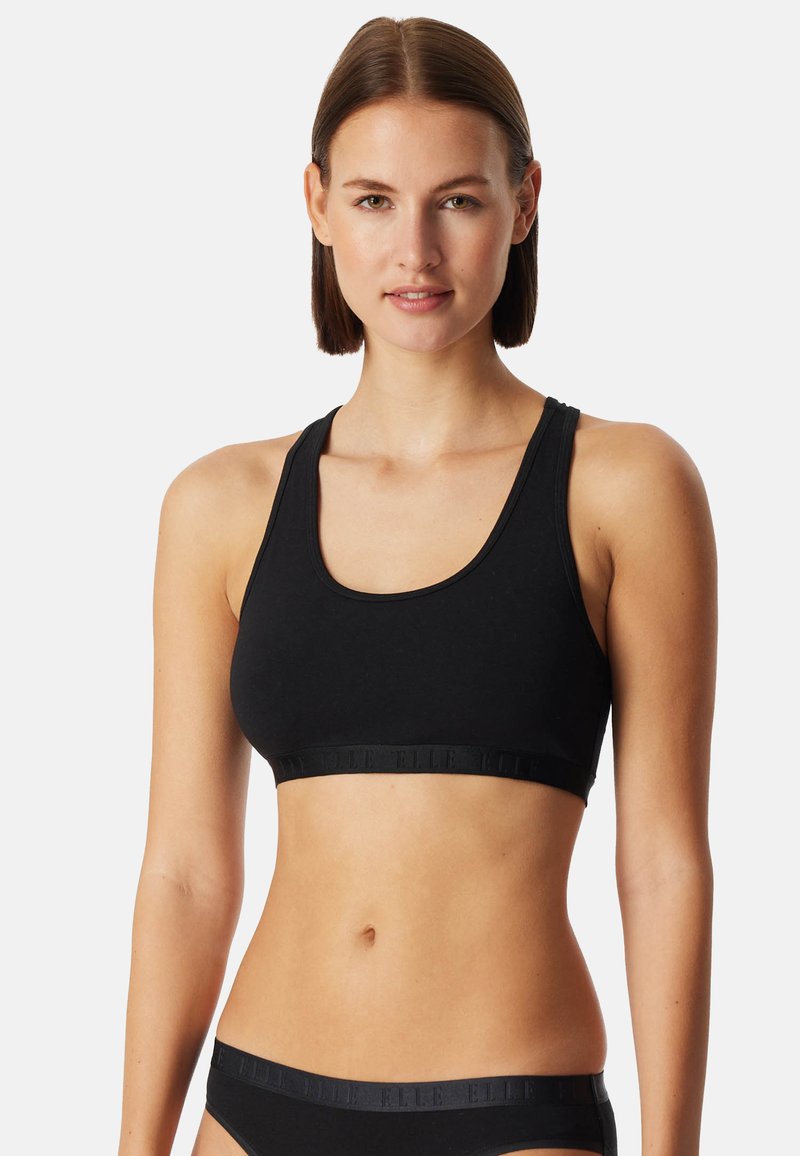 Mustavärinen urheiluliivimalli, joka on istuva ja valmistettu sileästä materiaalista. Varustettu leveillä hihnoilla ja brändillä varustetulla kuminauhalla alareunassa.