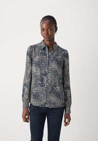Patterned navy button-up shirt with light beige polka dots, long sleeves, and a collar. Made from a lightweight fabric. Smooth texture.